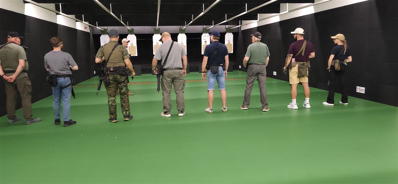 Grupa uczestników zajęć przed tarczami na krytej osi Strzelnicy Bydgoszcz